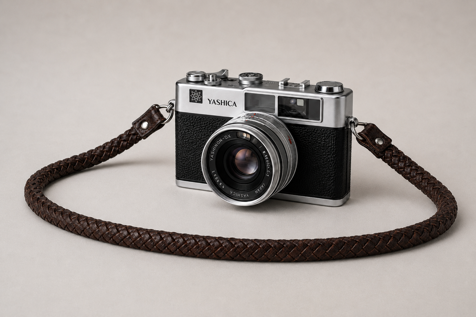 Vintage film camera with a brown braided leather strap used as a camera strap
