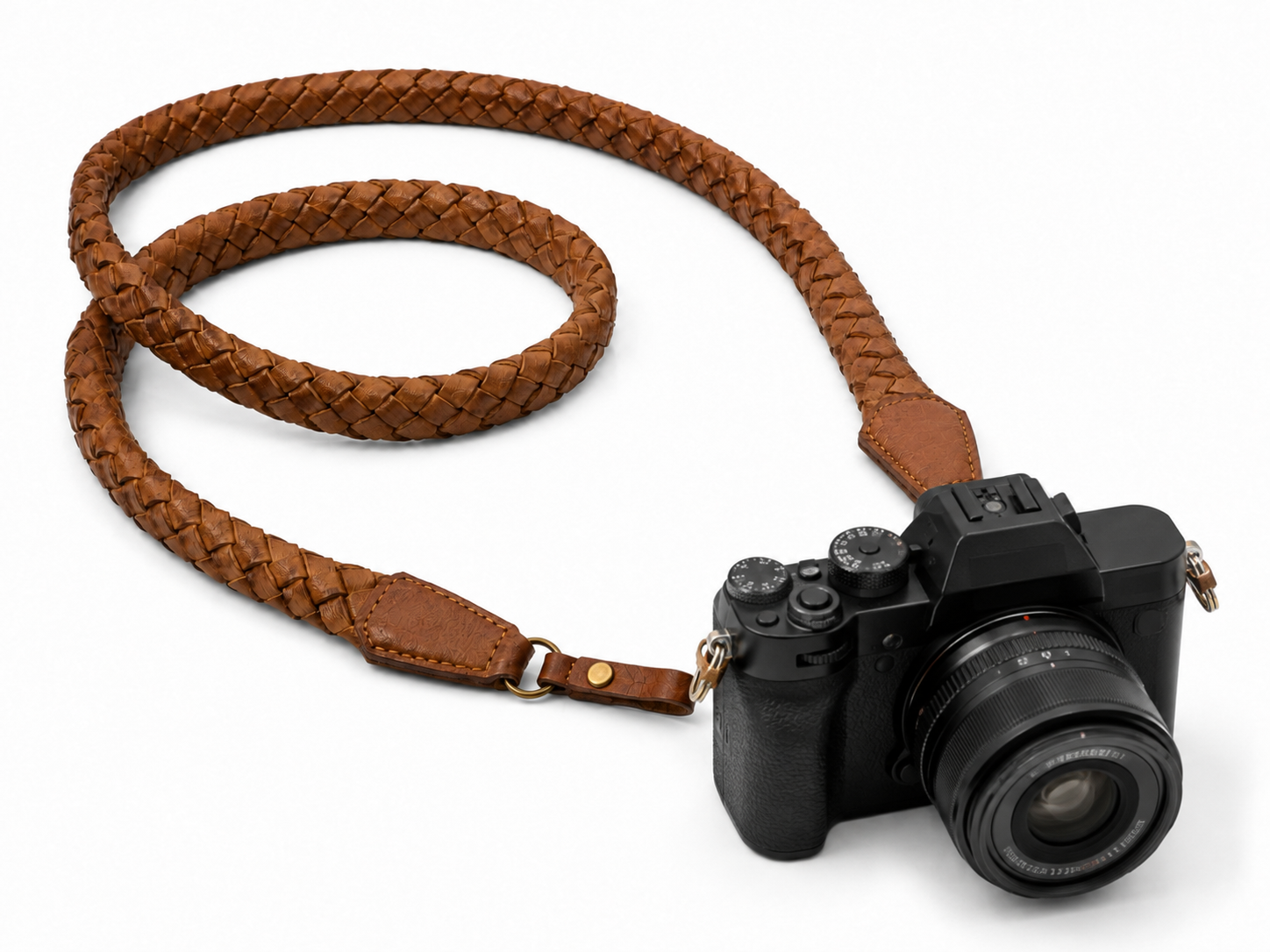 Tan braided leather strap used as a camera strap on a black mirrorless camera, with brass hardware